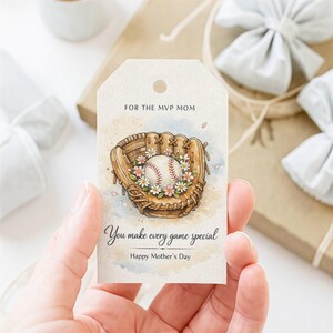 May include: A baseball-themed gift tag with a watercolour design. The tag features a baseball glove with a baseball adorned with flowers. Text reads "For the MVP Mom," "You make every game special," and "Happy Mother's Day."