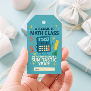 May include: A rectangular teal gift tag featuring the text WELCOME TO MATH CLASS and WE'RE GONNA HAVE A SUM-TASTIC YEAR! The design includes a cartoon calculator with the screen reading 1+2=3, a yellow ruler, a green triangle, and a From: line.