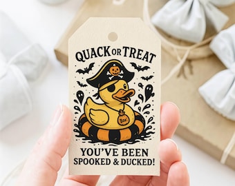 May include: A rectangular cream-colored gift tag featuring a yellow rubber duck wearing a pirate hat with a pumpkin icon, an eyepatch, and a necklace with a Boo tag. The duck sits in a black and orange striped floatie with bats and ghosts.