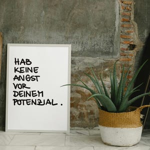 Könnte beinhalten: Ein weißer gerahmter Poster mit schwarzem Text, der "HAB KEINE ANGST VOR DEINEM POTENZIAL." lautet.