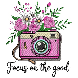 May include: Pink and beige camera illustration with a bouquet of pink roses, white daisies, and green leaves. The phrase "Focus on the good" is written in black script below the camera.