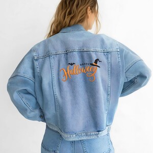 May include: Light blue denim jacket with "Happy Halloween" embroidered on the back. The design includes a bat and a witch's hat in black and orange. The jacket has a classic collar, button closure, and pockets.