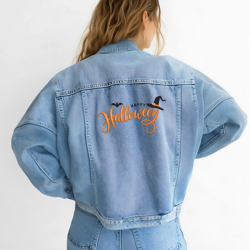 May include: Light blue denim jacket with "Happy Halloween" embroidered on the back. The design includes a bat and a witch's hat in black and orange. The jacket has a classic collar, button closure, and pockets.