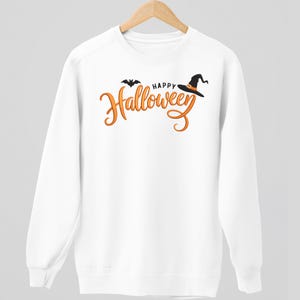 May include: White sweatshirt with the words "Happy Halloween" in orange script, a black bat, and a witch's hat. The design is centered on the front of the long-sleeved top. The sweatshirt is hanging on a wooden hanger.