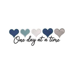 May include: Embroidered design featuring five hearts in shades of blue, teal, white, and gray, arranged horizontally. The phrase "One day at a time" is written in cursive below the hearts, all on a white background.