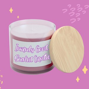 以下が含まれることがあります： 木製の蓋が付いた透明なガラス瓶に入ったピンク色の香り付きキャンドル。「Incredibly Good Scented Candle」と筆記体で書かれたラベル。キャンドルは、装飾要素のある紫色の背景にあります。