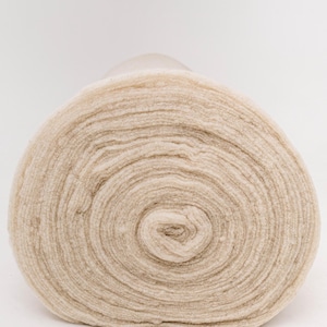 May include: A rolled-up fabric, beige in colour, showing a spiral pattern created by the layers. The material has a soft, textured appearance. The neutral colour palette is set against a plain white background. The fabric is likely for crafts.