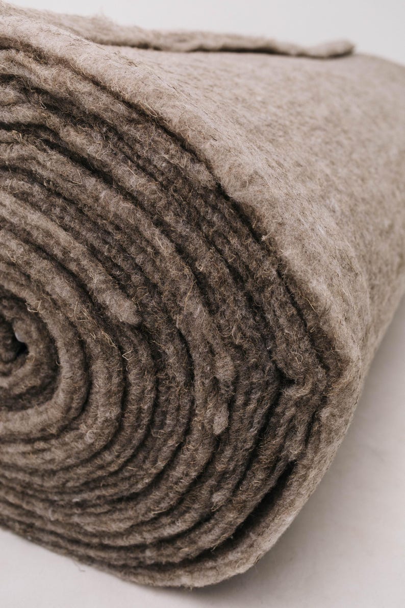 K&ouml;nnte beinhalten: Ein aufgerolltes, dickes, braunes Filzmaterial. Der Filz hat eine dichte, strukturierte Oberfl&auml;che mit sichtbaren Fasern. Die Rolle ist eng gewickelt und zeigt konzentrische Kreise des Materials. Die Farbe ist ein ged&auml;mpftes, erdiges Braun.