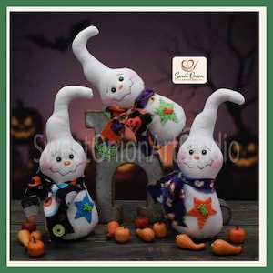 May include: Three white fabric ghost figurines with stitched facial features, orange noses, and pink cheeks. Each ghost wears a patterned scarf and has a felt star appliqué. They are arranged around a grey metal letter H with small orange gourds.