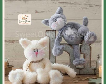 May include: Two plush cat toys, one cream-coloured and one grey, featuring soft fur, stitched facial details, pink noses, and long whiskers. The grey cat is positioned atop a large, weathered metal letter N, while the cream cat sits below.
