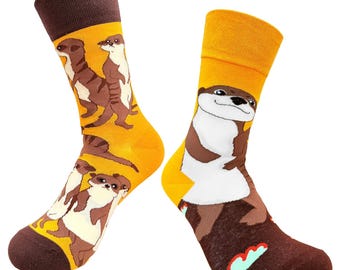 May include: A pair of novelty socks featuring a brown and white otter design on a yellow background. The socks have brown heels and toes. The otter design is repeated on both socks.