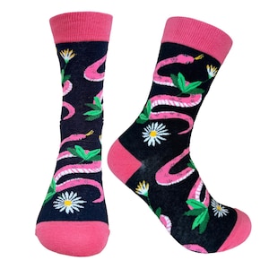 Könnte beinhalten: Ein Paar schwarze Socken mit einem rosa Schlangen- und Blumenmuster. Die Socken haben rosa Zehen, Fersen und Bündchen. Die Schlange ist rosa mit weißen Streifen, und die Blumen sind weiß mit gelben Zentren.