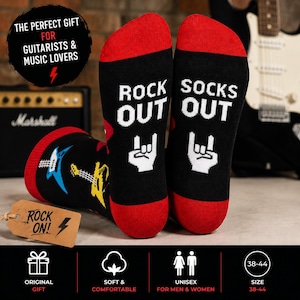 Pode incluir: Meias pretas com punhos e dedos vermelhos, com o texto "ROCK OUT" e um gesto de mão. Outra meia exibe "SOCKS OUT". Uma etiqueta diz "ROCK ON!". Presente unissex para amantes da música.