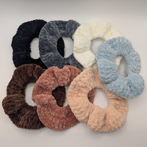 Puede incluir: Una colección de siete coleteros de felpa en varios colores. Los coleteros son en tonos negro, gris, crema, azul claro, marrón, rosa empolvado y melocotón. Los coleteros están hechos de un material suave y texturizado.