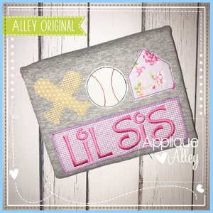 May include: A gray t-shirt with pink embroidered designs. The designs include a baseball, a plane, a house, and the text "Lil Sis".