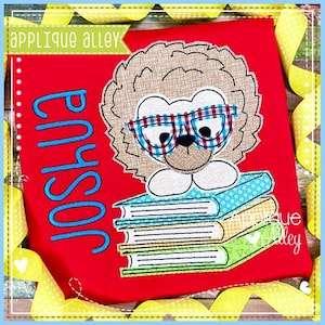 May include: A brown lion wearing glasses is sitting on a stack of colourful books. The lion is wearing a red and white checked shirt. The text "Joshua" is embroidered in blue on a red shirt. The text "Applique Alley" is in green on a white background.