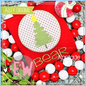 Könnte beinhalten: Rotes Shirt mit einem weißen Kreis-Applique, das einen grünen Weihnachtsbaum mit einem gelben Stern oben zeigt. Das Shirt hat das Wort "Bear" in goldener Farbe unter dem Applique gestickt.