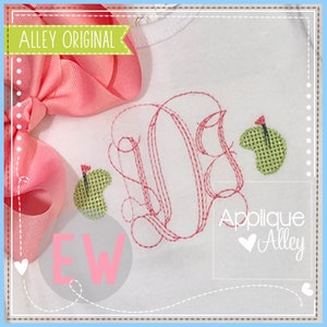 May include: A white shirt with a red embroidered monogram and two green golf ball appliques. The text "Applique Alley" is in the bottom right corner of the shirt.