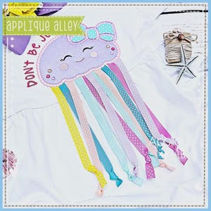 May include: A white t-shirt featuring a lavender jellyfish applique with a teal polka dot bow. The jellyfish has a smiling face and long, colorful ribbon tentacles in yellow, pink, teal, and purple. The text DON'T BE JELLY is embroidered in red.
