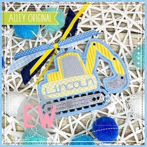 May include: A blue and yellow embroidered excavator applique with the name "Lincoln" stitched on the side. The applique is attached to a blue and white gingham ribbon and a yellow ribbon.