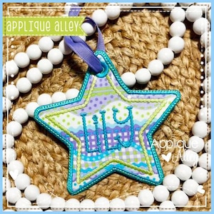 May include: A star-shaped, personalised ornament embroidered with the name "Lily" in blue. The ornament has a teal border and a purple ribbon for hanging. The background is a woven texture, and white beads surround the ornament. The text "Applique Alley" is visible.