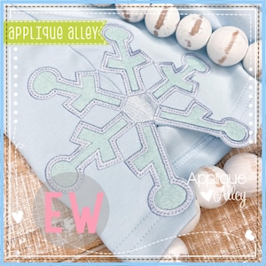 Pode incluir: Um tecido azul claro com uma aplicação de floco de neve branco. O floco de neve é contornado de branco e preenchido com uma cor verde claro. O tecido tem o texto "Applique Alley" em letras brancas.