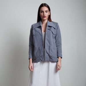 May include: A woman wearing a blue and white patterned jacket with a white skirt and cork platform sandals.