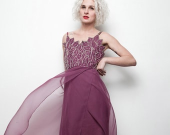 May include: A woman wearing a long, flowing, mauve-colored gown with a beaded bodice. The gown has a high slit and a sheer overlay. She is wearing nude heels.