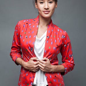 May include: A woman wearing a red and white patterned jacket with a white t-shirt and a black leather skirt.