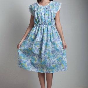 May include: A blue and white floral dress with a lace trim and a gathered waist. The dress is knee-length and has short sleeves.