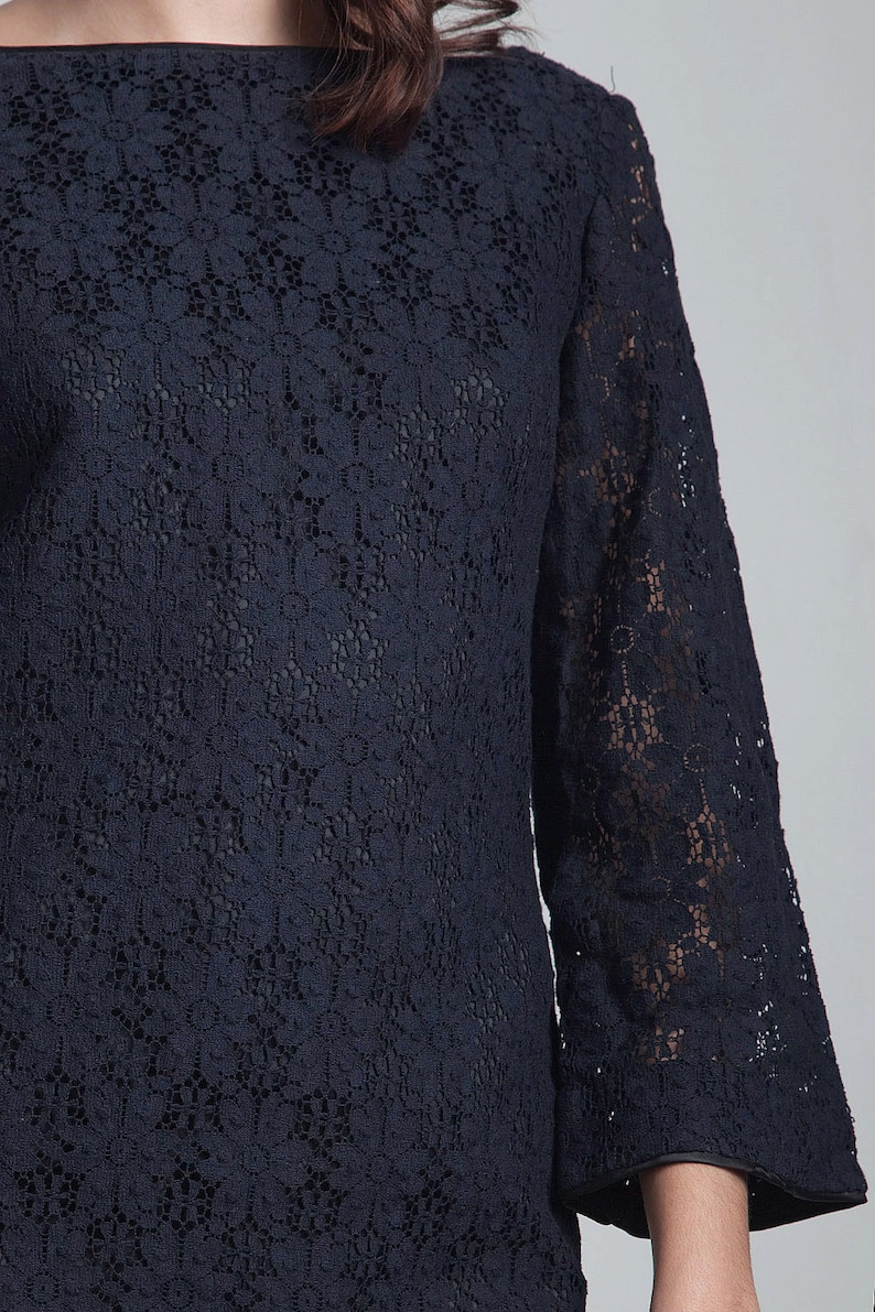 May include: A navy blue lace top with a boat neck and three-quarter sleeves.