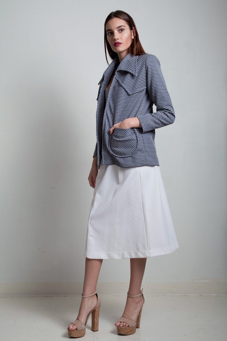 May include: A woman wearing a white skirt and a blue and white patterned jacket. She is wearing cork platform heels.