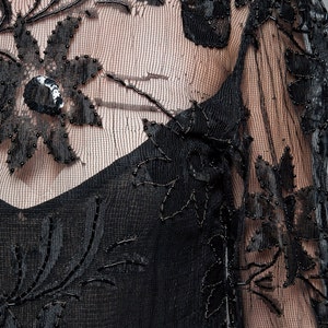 May include: Black sheer fabric with floral embroidery and beading. The fabric is delicate and has a vintage feel.