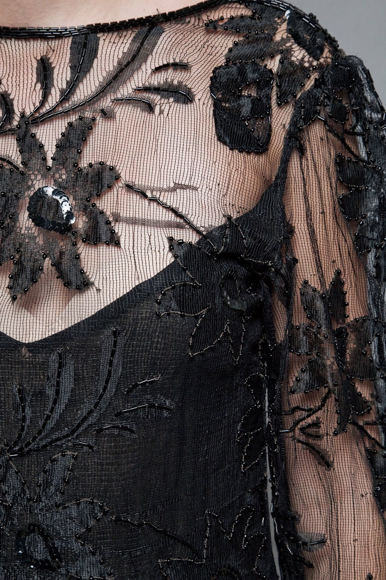 May include: Black sheer fabric with floral embroidery and beading. The fabric is delicate and has a vintage feel.