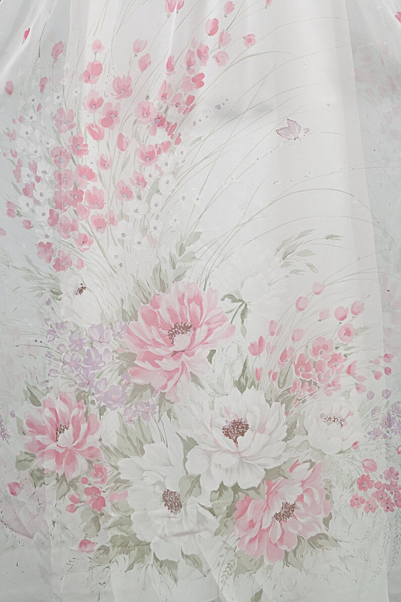 May include: White fabric with a pink floral pattern. The flowers are painted in shades of pink and white, with green leaves and stems. There are also small pink flowers scattered throughout the fabric.
