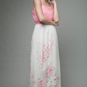 May include: A woman wearing a pink and white floral maxi dress. The dress has a pink bodice and a white skirt with pink floral print.
