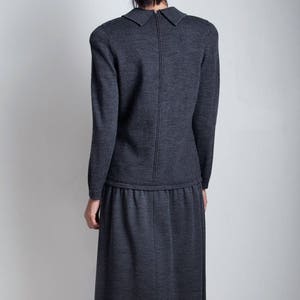 May include: A charcoal gray knit dress with a collared neckline and a long skirt. The dress has a zipper down the back.