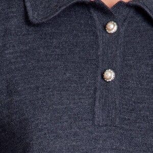 May include: A dark gray knitted collared shirt with pearl buttons.