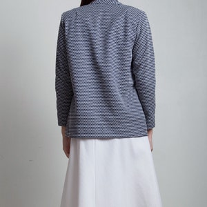May include: A white skirt with a navy blue and white patterned blazer. The blazer has a long sleeve and a collar.