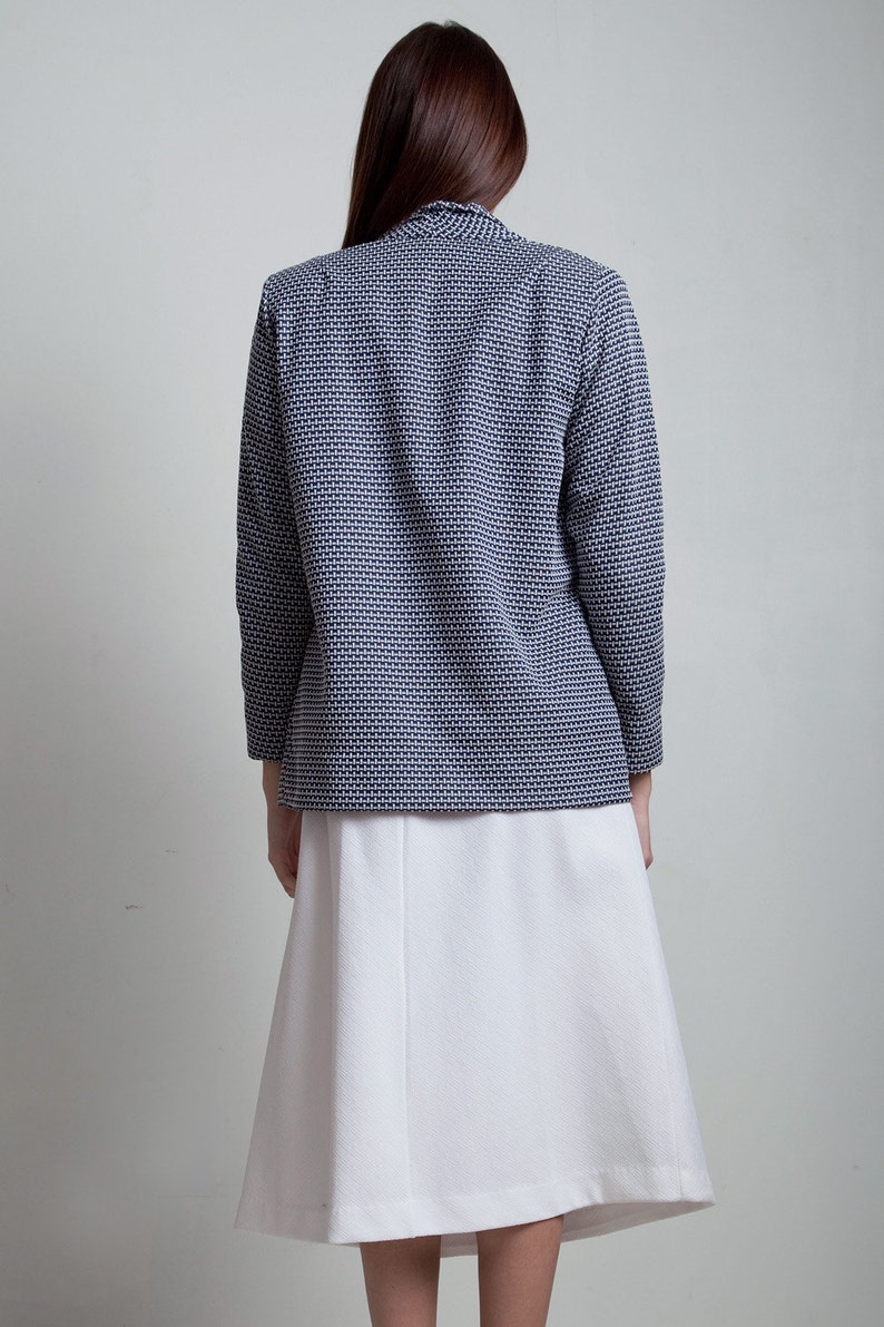 May include: A white skirt with a navy blue and white patterned blazer. The blazer has a long sleeve and a collar.