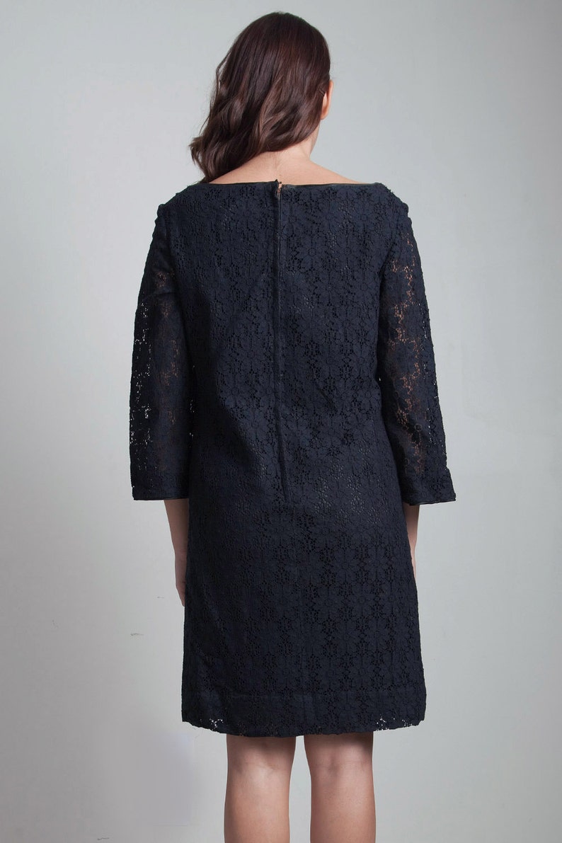 May include: A black lace dress with a scoop neckline and 3/4 sleeves.
