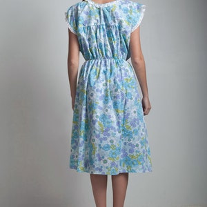 May include: A blue and white floral midi dress with a white lace trim on the neckline and sleeves. The dress has a cinched waist and a flowy skirt.