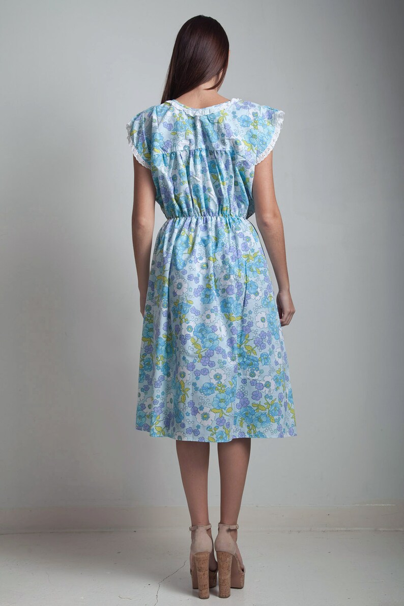 May include: A blue and white floral midi dress with a white lace trim on the neckline and sleeves. The dress has a cinched waist and a flowy skirt.