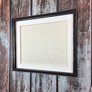 May include: A black and white picture frame with a distressed finish. The frame is made of wood and has a white inner border. The frame is empty and ready to be filled with a photo or artwork.
