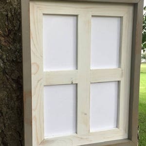 Peut inclure: Un cadre photo blanc avec une bordure extérieure grise. Le cadre a quatre ouvertures pour photos. Le cadre est en bois et a un aspect rustique.