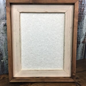 May include: A wooden picture frame with a light brown inner frame and a dark brown outer frame.