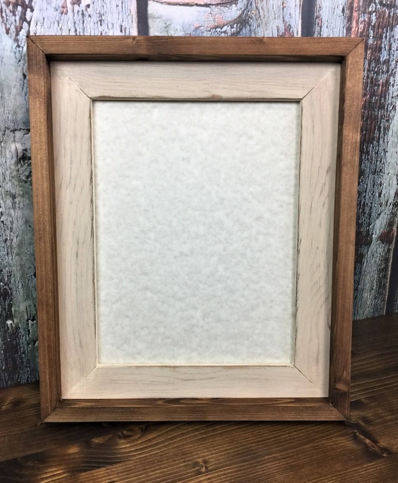 May include: A wooden picture frame with a light brown inner frame and a dark brown outer frame.