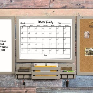 May include: A wooden wall organizer with a dry erase board, calendar, and corkboard. The dry erase board is 11 1/2 inches wide and 26 inches tall. The calendar is labeled "Watts Family". The organizer includes a mail and key holder.
