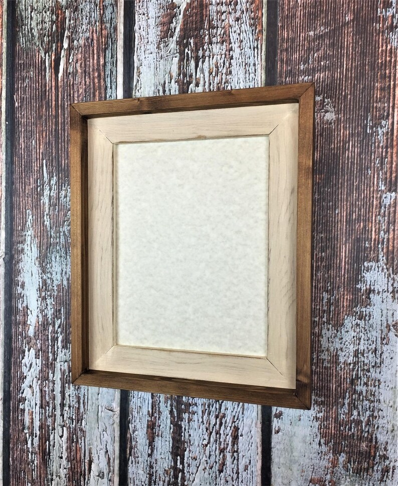 May include: A wooden picture frame with a natural wood finish. The frame has a double border, with a darker brown outer border and a lighter natural wood inner border.