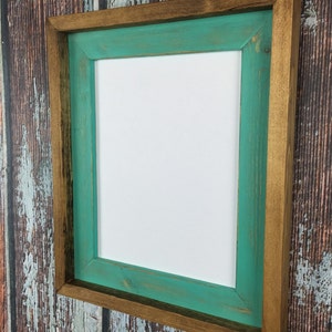 May include: A rustic wooden picture frame with a teal green inner border. The frame has a distressed finish and is perfect for adding a touch of farmhouse charm to your home decor.